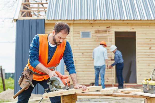 Handwerker mit Handkreissaege beim Hausbau