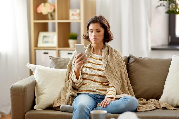 Frau sitzt auf Sofa mit Extra Strickpullover