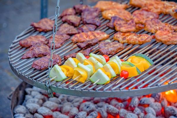 Allerlei Grillgut liegt auf einem Schwenkgrill, der über einer Feuerschale hängt