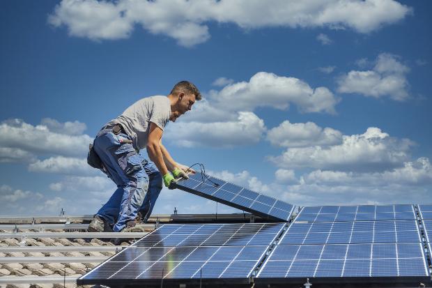 Zwei Arbeiter installieren eine Photovoltaikanlage auf einem Dach