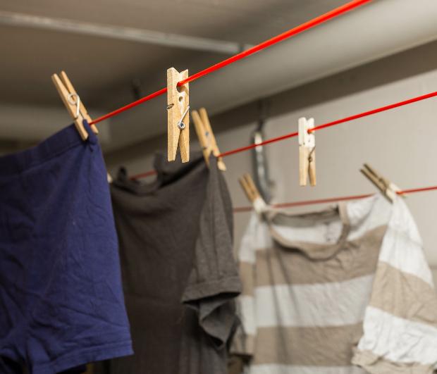In der Waschküche im Keller sind mehrere Kleidungsstücke zum Trocknen aufgehängt Kellerlüfter gegen Feuchtigkeit