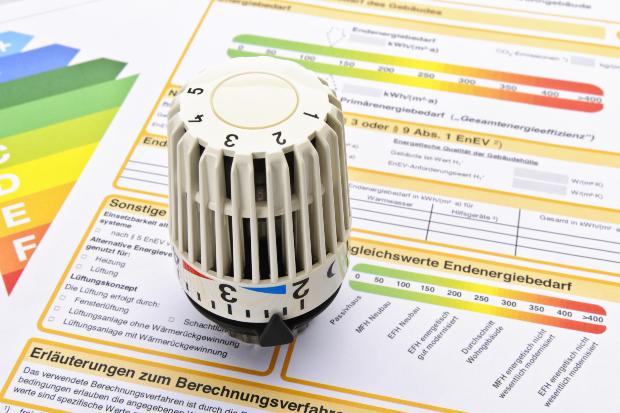 Ein Thermostat liegt auf einem Formular zur Heizungsförderung
