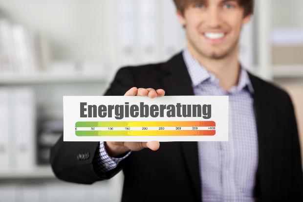 Ein Mann präsentiert ein Schild auf dem "Energieberatung" steht