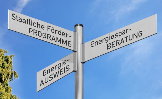 Ein Symbolbild zeigt einen Wegweiser mit den Schildaufschriften: "Staatliche Förderprogramme", "Energiesparberatung" und "Energieausweis" Förderung bei der Heizungsumstellung
