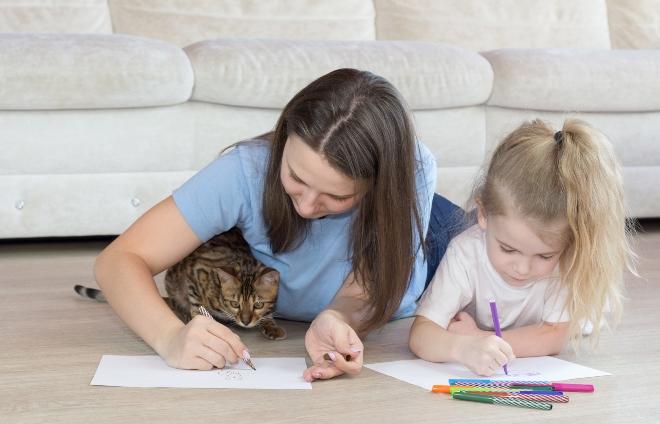 Mutter mit Katze und Kind malen auf dem Boden liegend