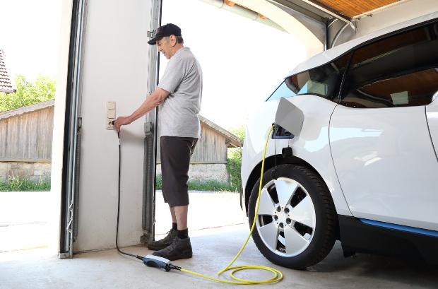 Ein Mann lädt sein E-Auto an einer gewöhnlichen Steckdose 