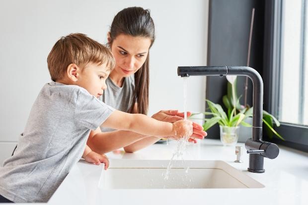 Mutter mit Kind am Wasserhahn in der Küche