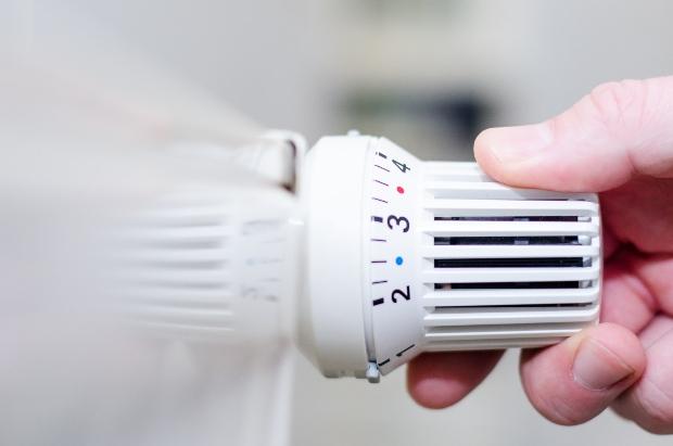Heizungsthermostate - Nahaufnahme, Hand stellt Thermostat ein