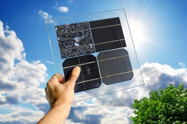Jemand hält ein Muster unterschiedlicher kristalline Photovoltaikmodule vor dem blauen Himmel in die Höhe