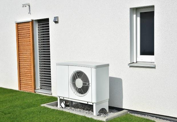 Eine kleine Luftwärmepumpe vor einem Einfamilienhaus Wärmepumpe für das Einfamilienhaus
