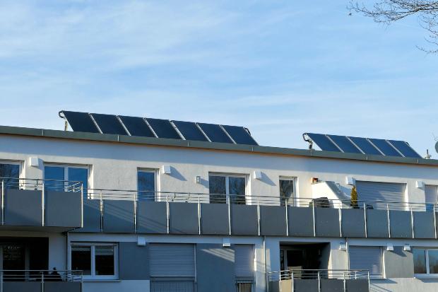 Ein Wohnhaus mit Flachdach auf dem eine Photovoltaik-Anlage installiert ist 