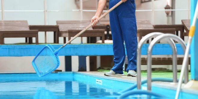 Mann bei der Poolreinigung mit einem Kescher