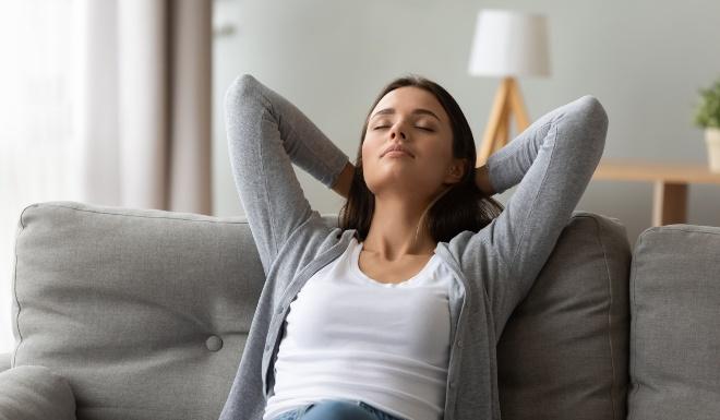 Junge Frau sitzt zuhause entspannt auf der Couch