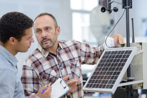 Zwei Ingenieure begutachten eine Solarzelle in einer Versuchsanordnung