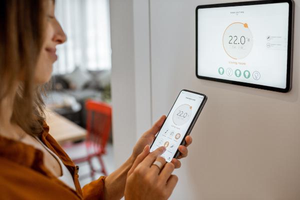 Eine Frau steuert mit dem Smartphone Heizung und verbundene Haustechnik Smart Heating