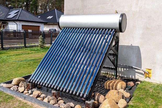 Vor einem Haus ist eine Solarthermieanlage zur Heizungsunterstützung aufgebaut 