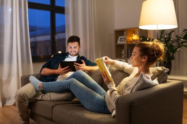 Junges Paar auf Couch im Wohnzimmer - Welche Raumtemperatur ist ideal?