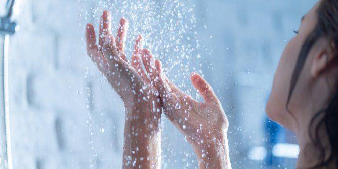 Frau in der Dusche - Warmwasserkosten senken