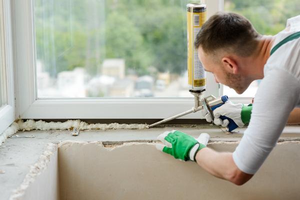 Ein Mann dichtet ein Fenster mit PU-Schaum ab