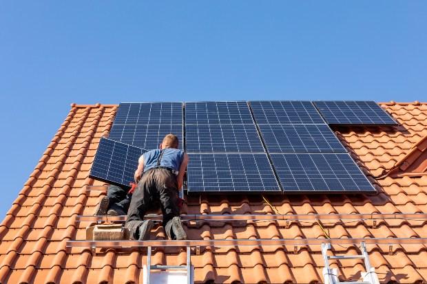 Mann installiert Photovoltaik-Anlage auf Hausdach