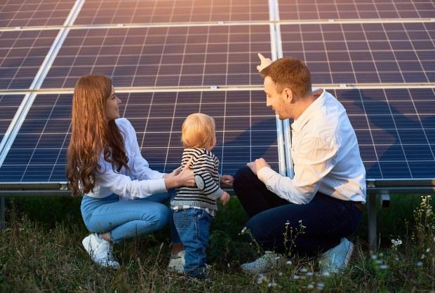 Junge Familie vor Photovoltaik-Anlage - Solarstrom einspeisen oder selbst verbrauchen?