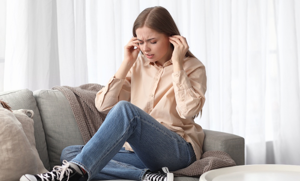 Ein dauerhaftes Brummen kann schnell zur psychischen Belastung werden Junge Frau benutzt Ohrstöpsel - Warum brummt die Heizung?
